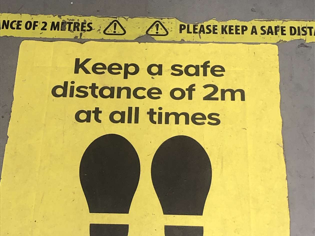 Photo: Pavement with notice to Keep safe distance of 2 meters